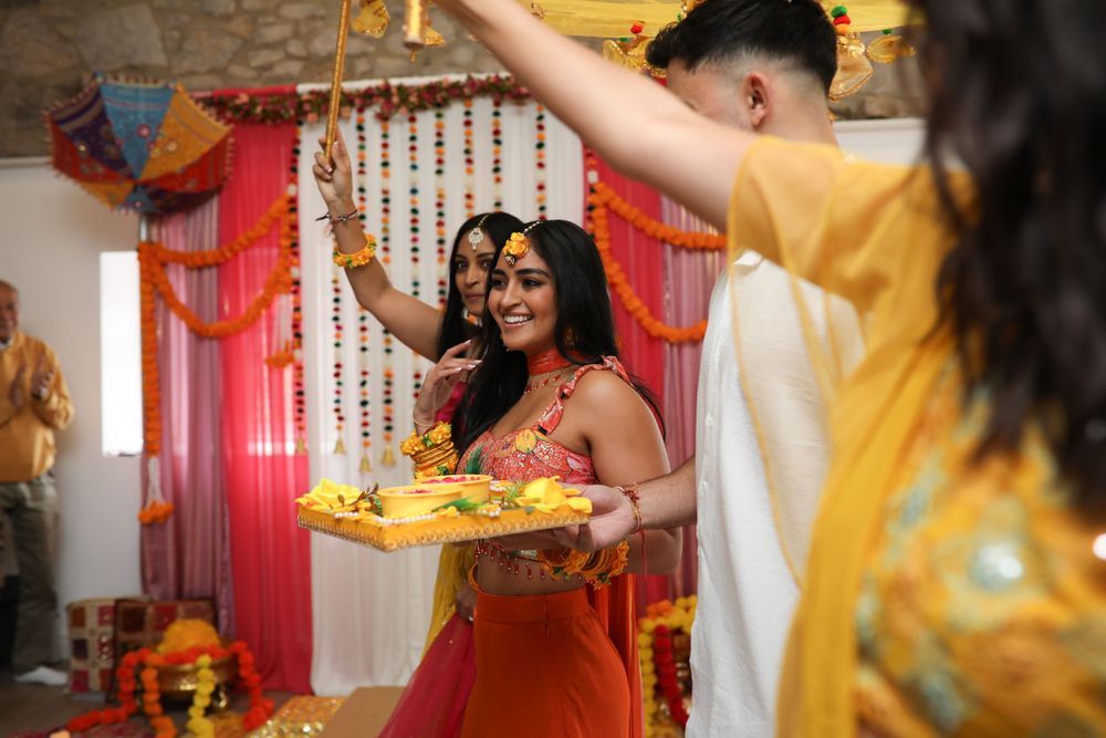 Celebratory Indian ceremony with yellow and red decorations and people holding plates.