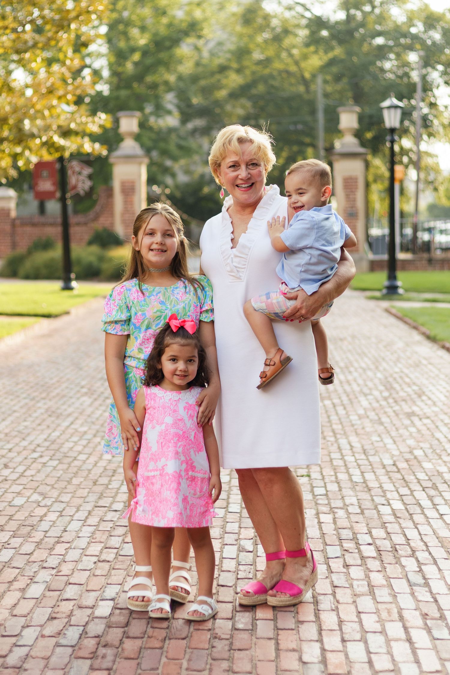A family portrait on a brick pathway with children in colorful Lilly Pulitzer dresses.