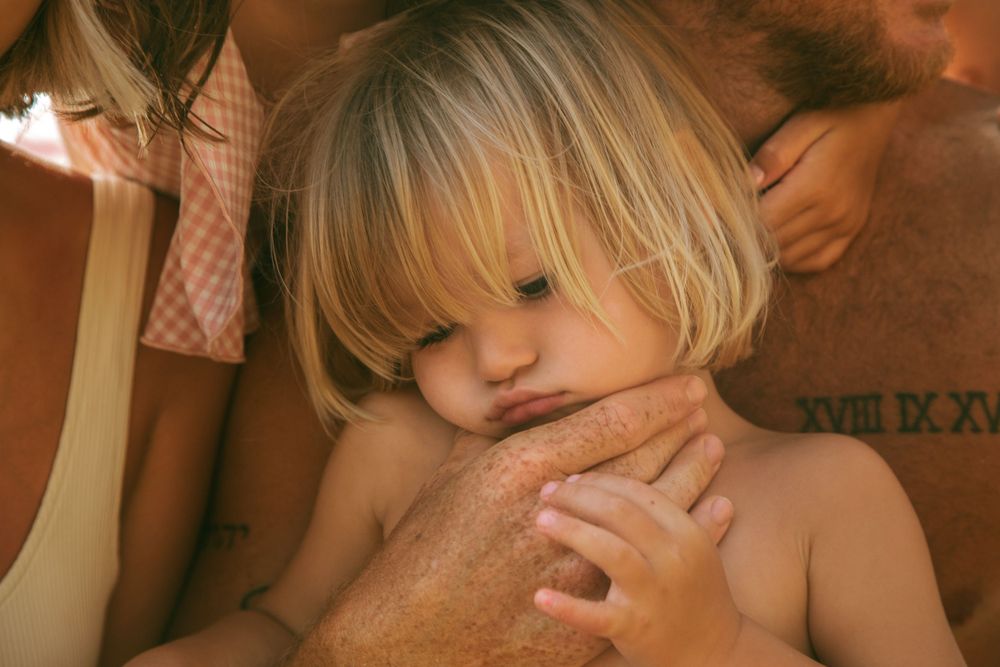 Close-up portrait of a small child with blonde hair in warm lighting.