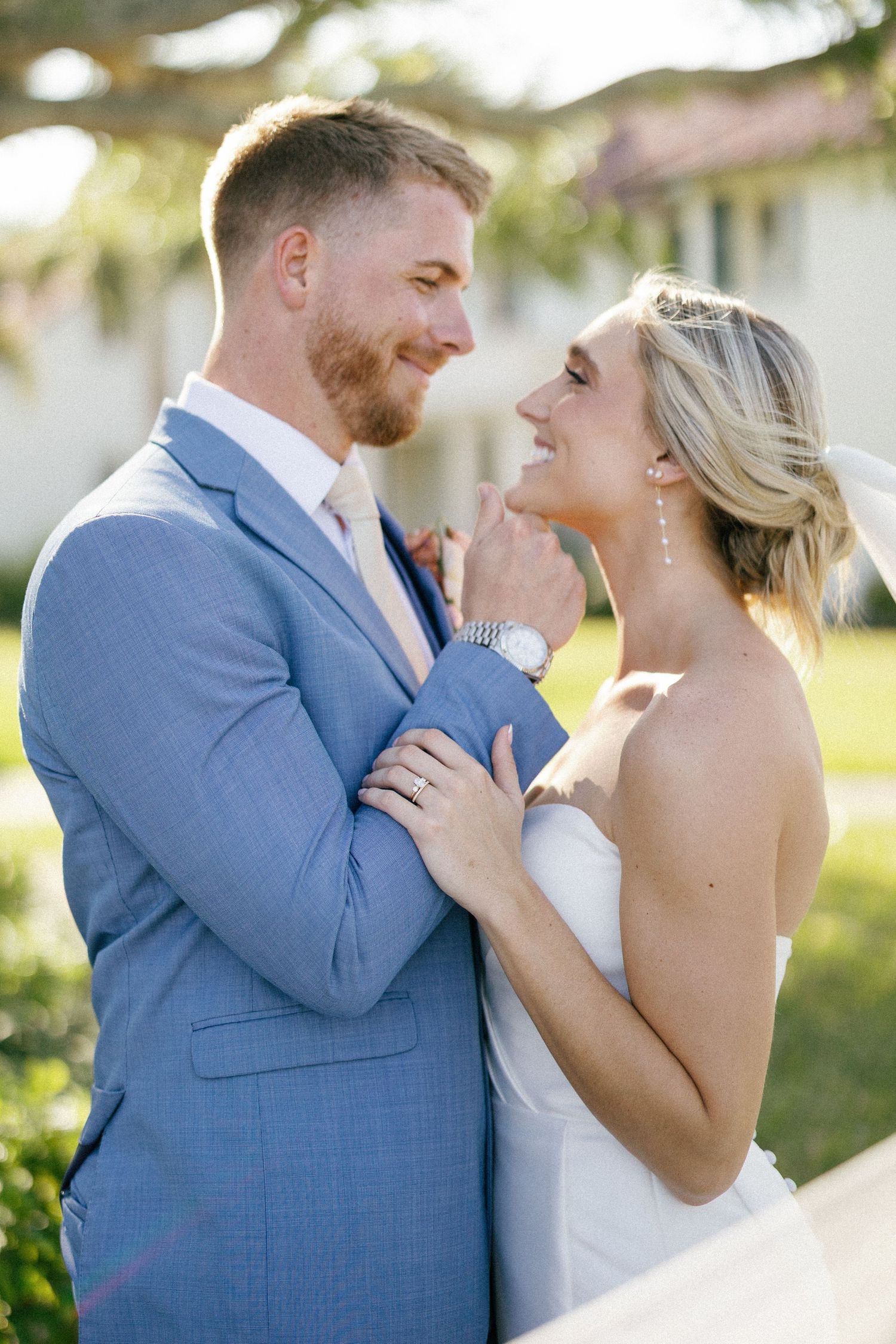 Wedding couple sharing intimate moment on garden path with flowing veil.