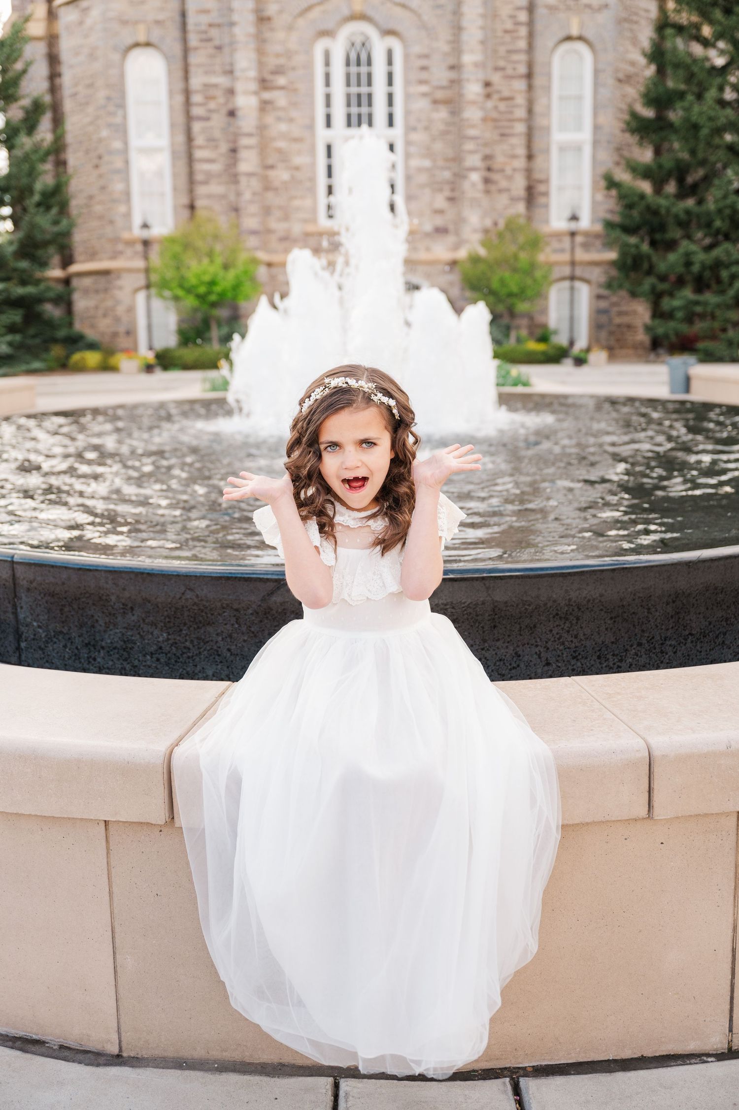 Playful portrait by fountain with temple architecture in background.