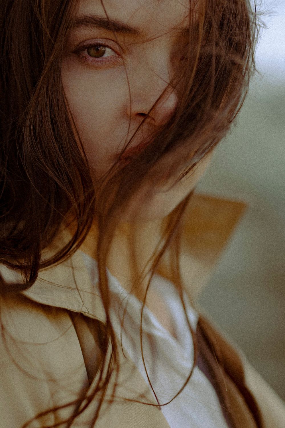 Moody close-up portrait with windswept hair in natural lighting.