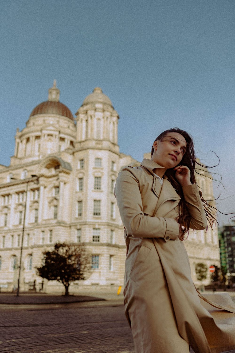 Artistic fashion photography against ornate Victorian architecture under blue sky.