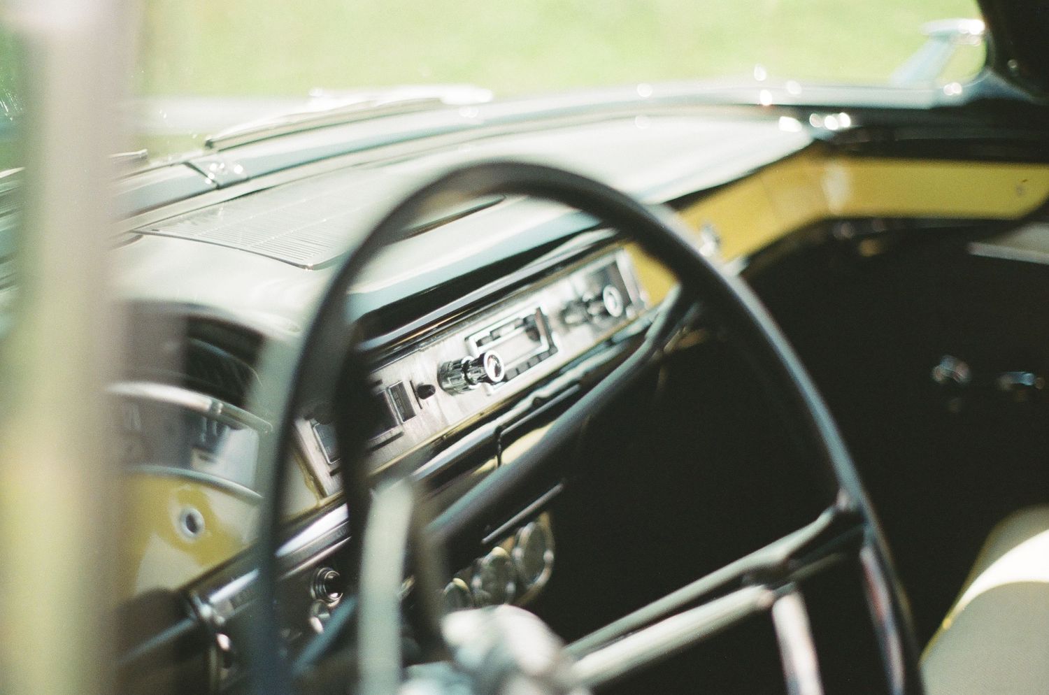 Close-up view of a vintage car dashboard showing classic steering wheel and gauges.