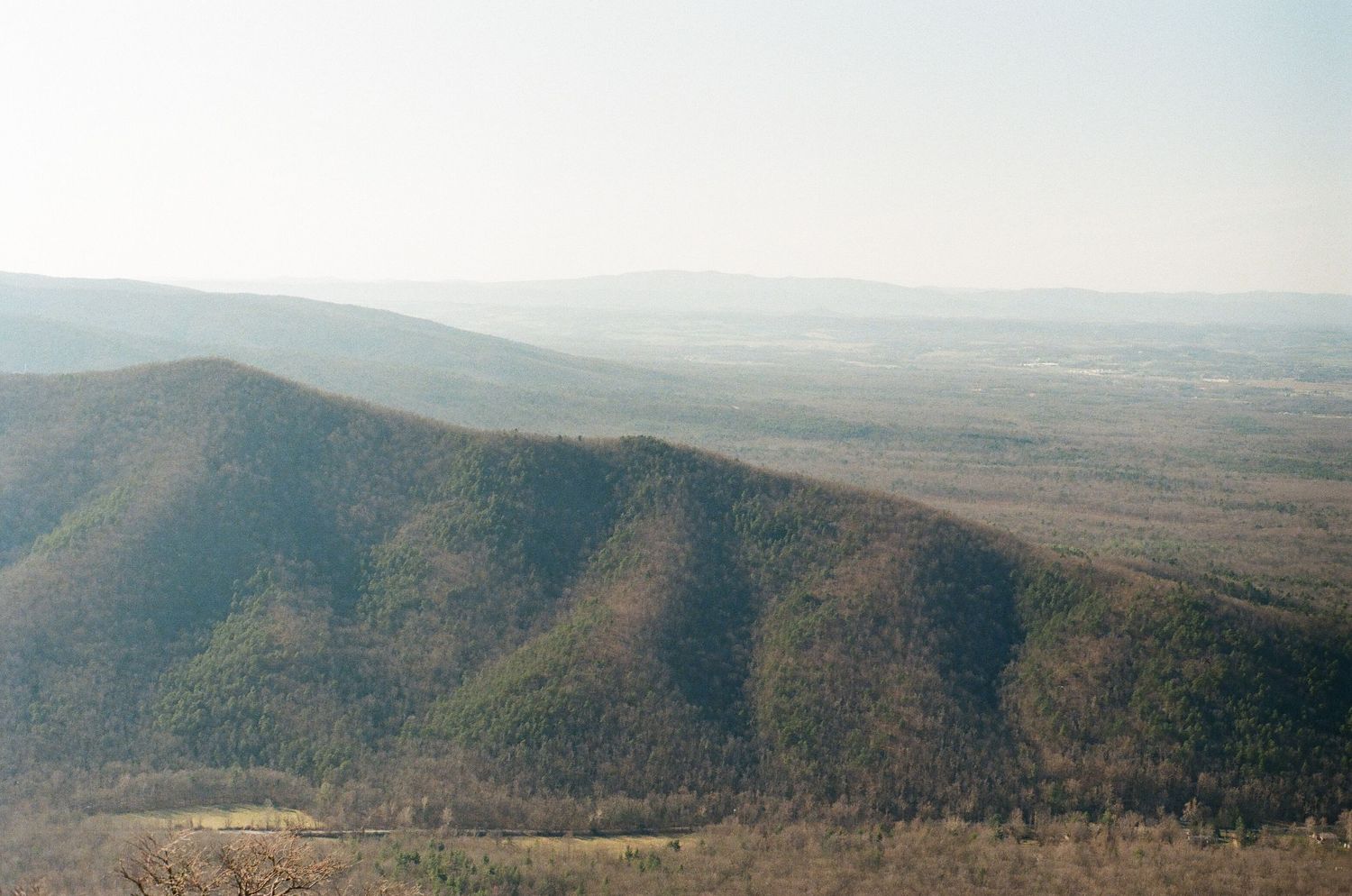 Rolling mountains fade into the distant horizon under a hazy sky in this scenic landscape view.