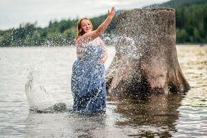 A person enjoys a playful moment splashing in the water with a horse on a sunny summer day.