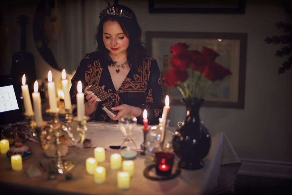 Woman at candlelit table with candelabra and red flowers.