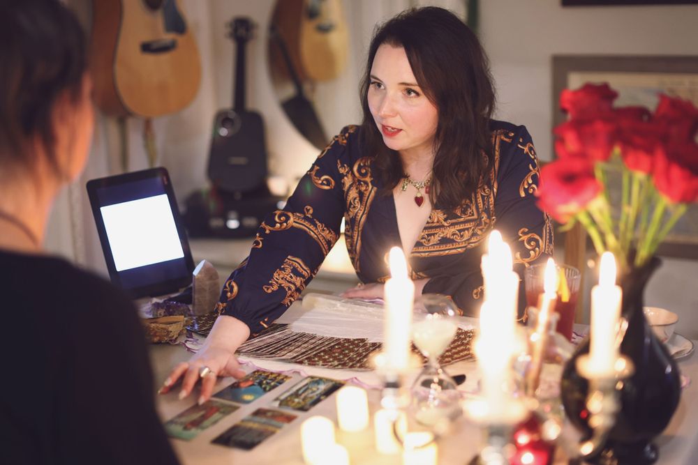 A mystical fortune telling session with candles and cards on a table with guitars hanging in background.