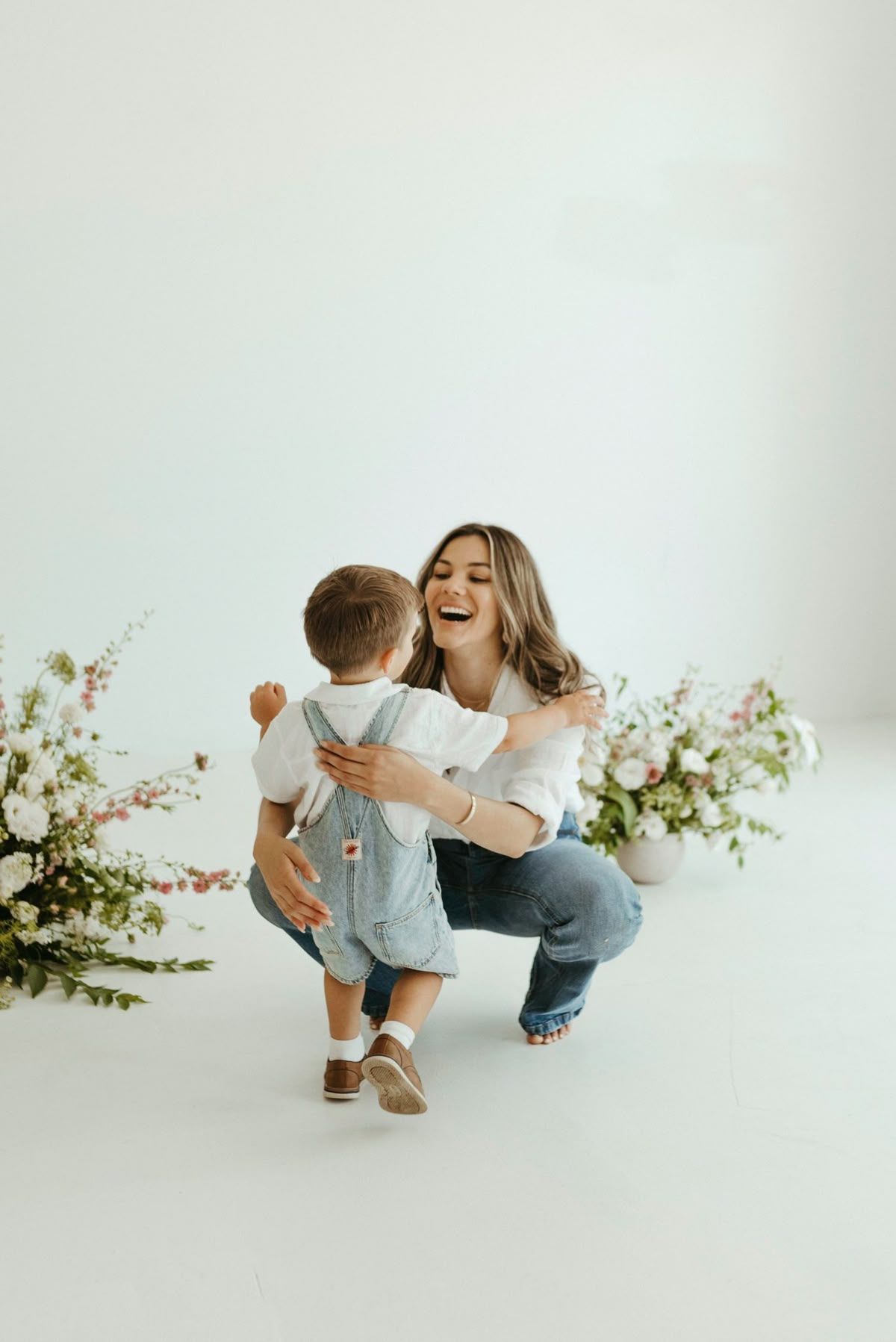 Four connected photos showing playful moments in a minimalist white studio with delicate floral arrangements.