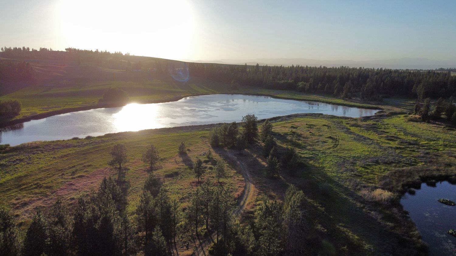 ariel view of sunset with a lake and large open and partially treed field in Spokane washington