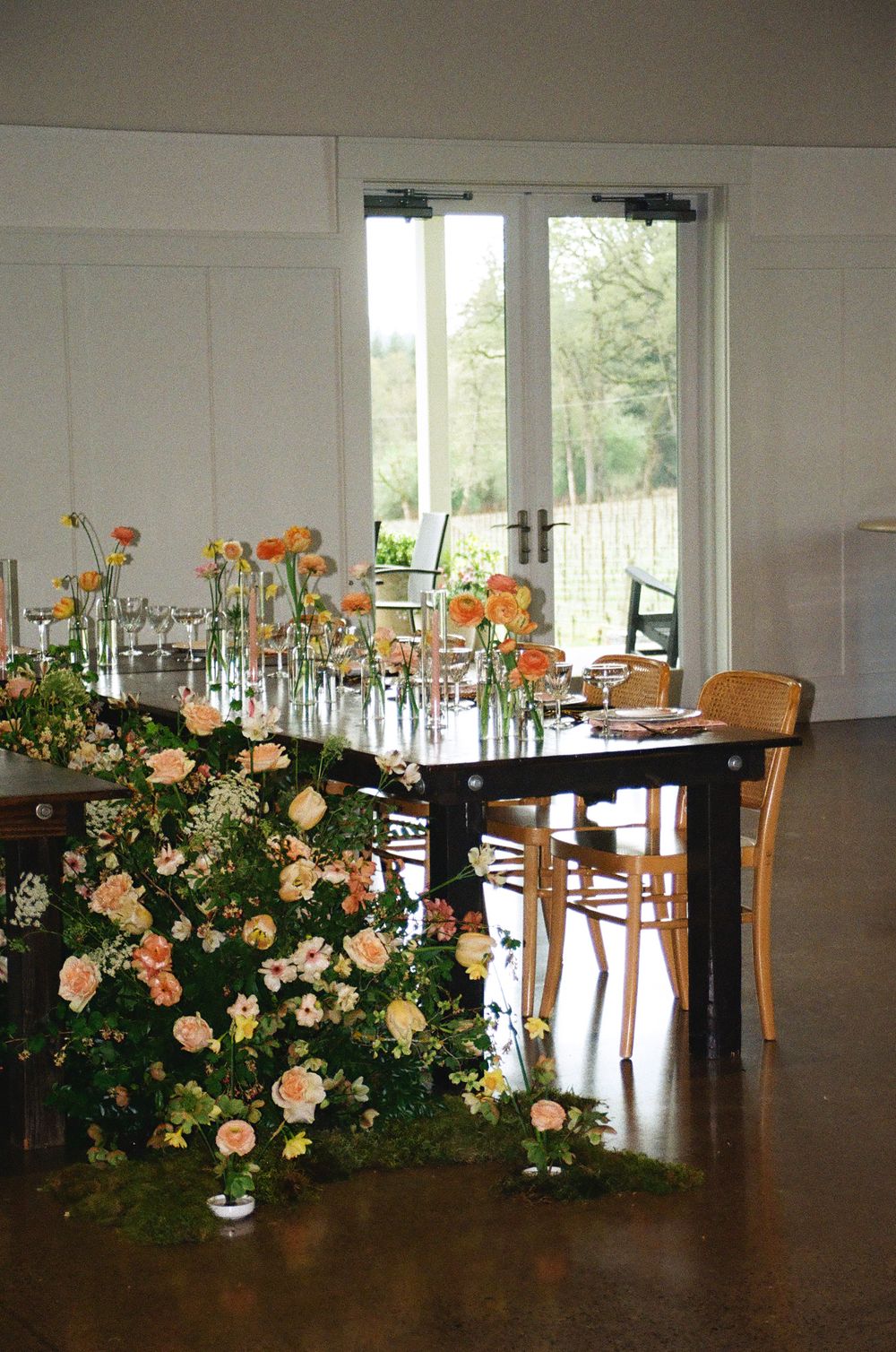 Elegant wedding reception table adorned with peach and orange floral arrangements and a lush garden floor installation.