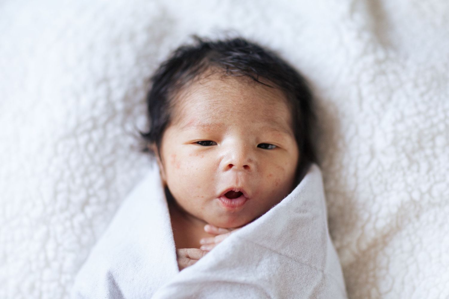 Seattle in-home newborn photographer: a close up photo of a swaddled 3-week-old baby in Everett WA