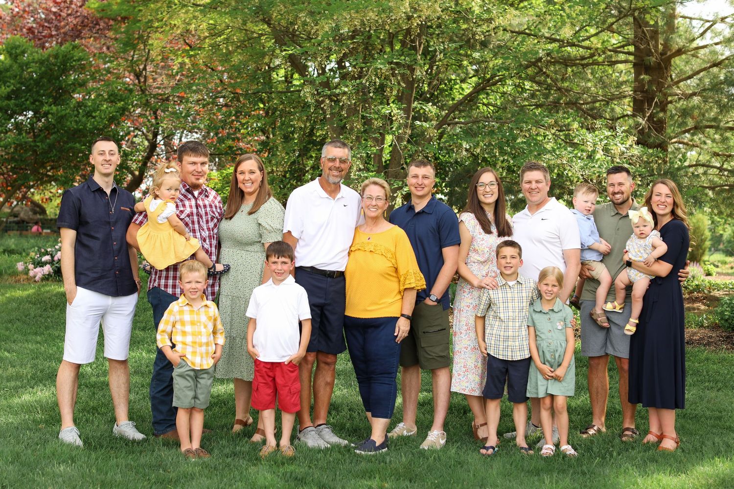 Large family group photo with coordinated outfits against a green garden backdrop.
