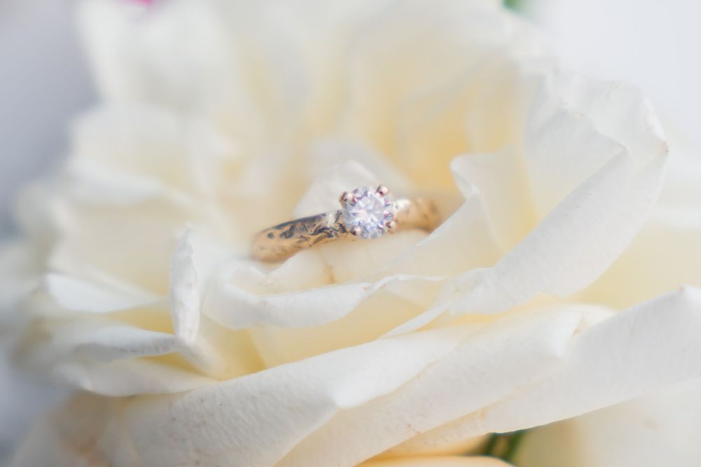 Diamond engagement ring nestled in soft white rose petals.