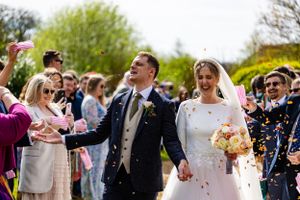 Wedding guests shower the couple with confetti as they celebrate on a spring day.