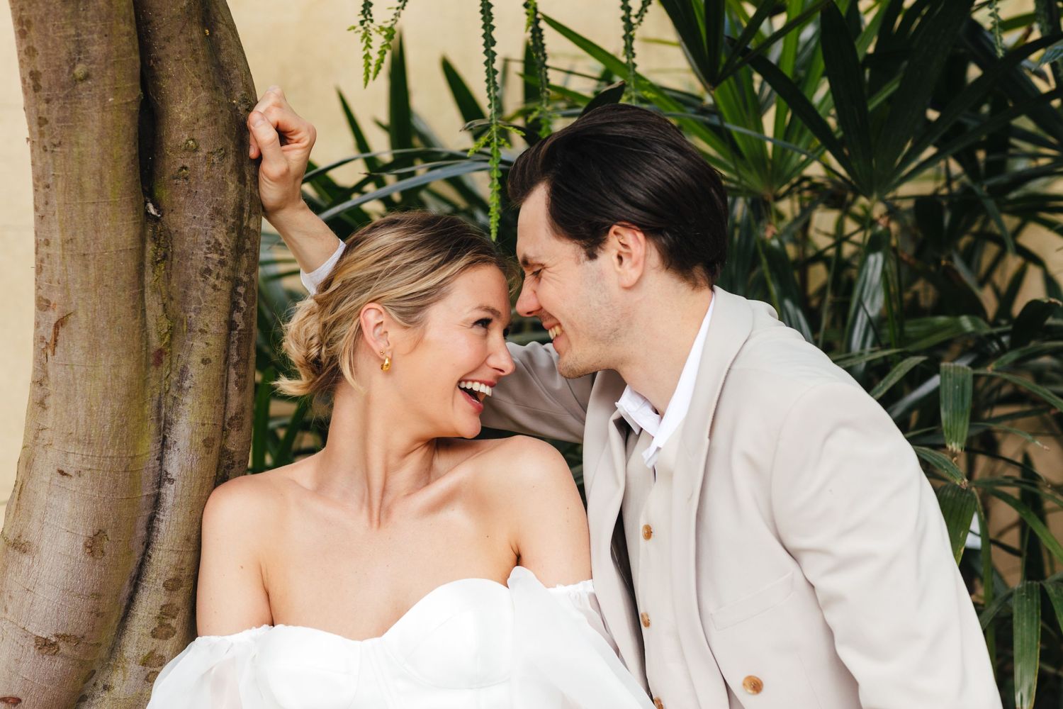 Intimate wedding portrait with couple sharing a romantic moment against tropical foliage.