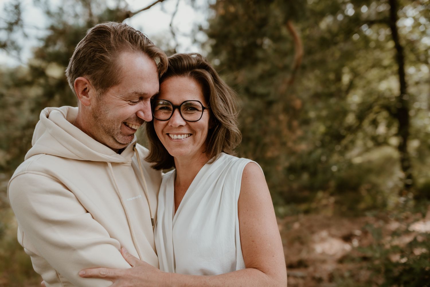 Een koppel houdt elkaar vast en lacht tijdens een familie fotoshoot