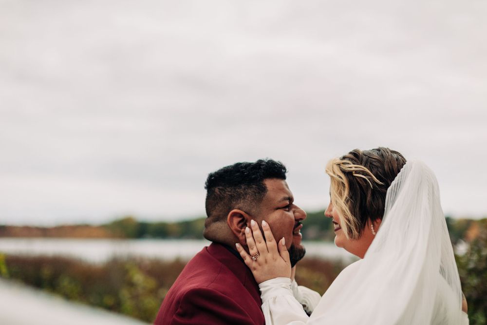 Tender wedding portrait showing close embrace with bride's veil flowing in the wind.