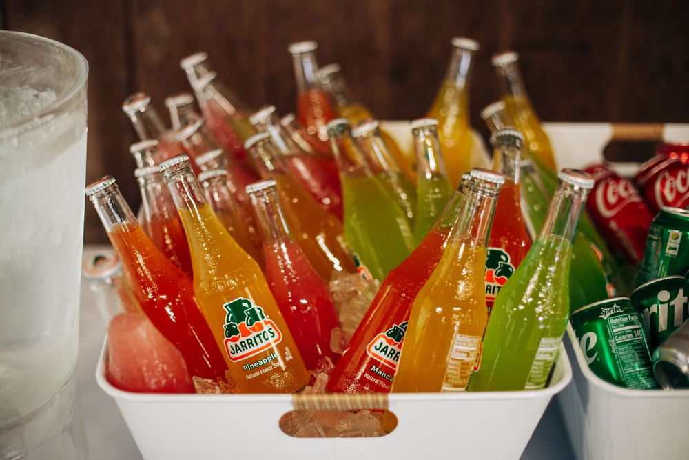 Colorful glass bottles of assorted sodas chilling in ice at a wedding reception.