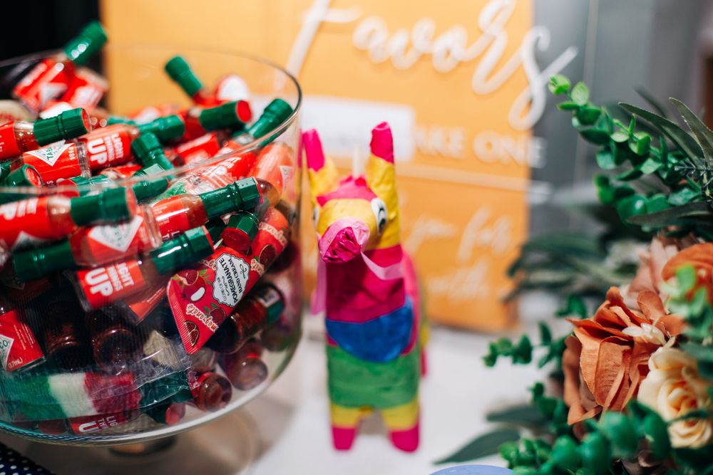 Colorful party decorations including candies in a glass jar and a vibrant rainbow-colored pinata on display.