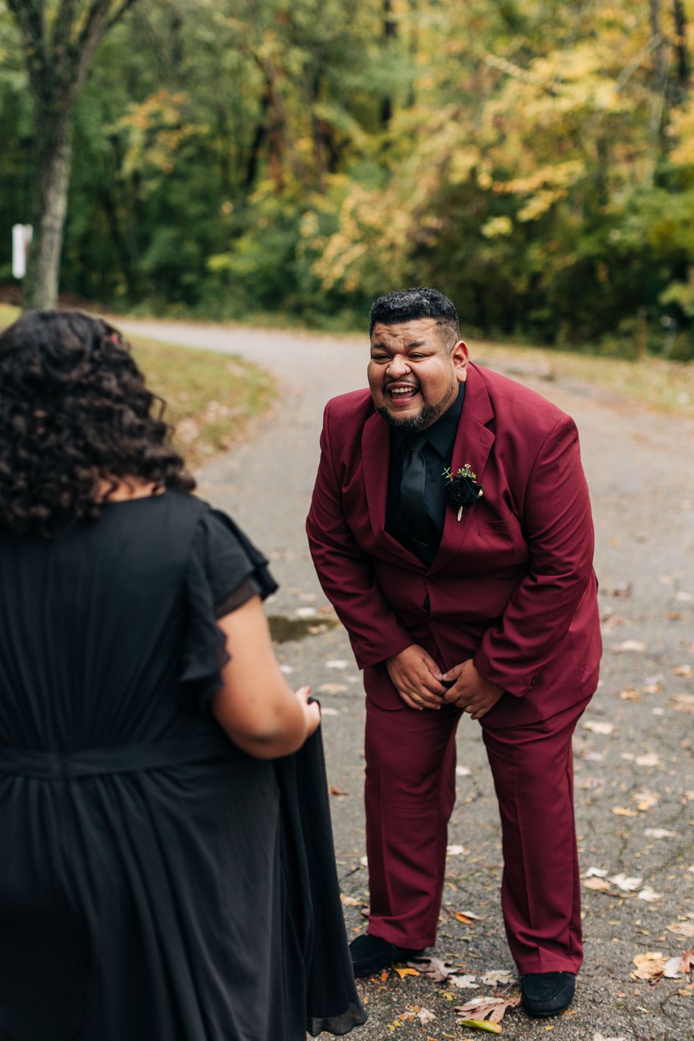 A joyful moment captured during an outdoor autumn wedding celebration on a leaf-covered path.