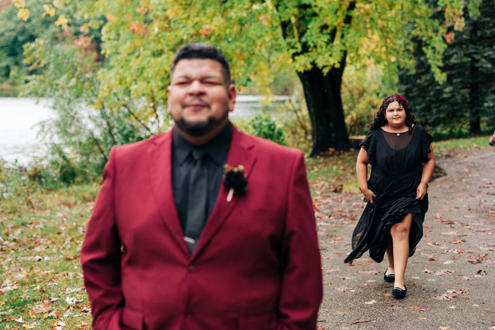 A candid first look moment during an autumn wedding with fall foliage and a lake in the background.