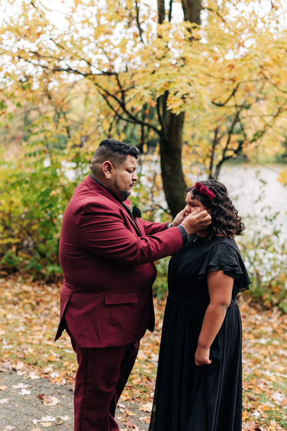 Two people share an emotional moment during their wedding ceremony surrounded by autumn leaves.