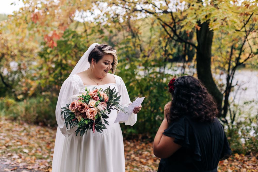 A wedding ceremony captured in a beautiful fall setting with vibrant bouquet and lakeside views.