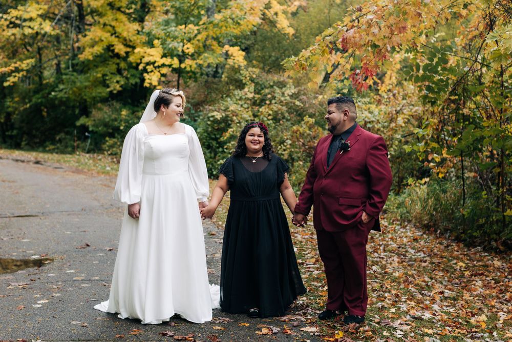 A wedding party poses together on a wooded path during a beautiful autumn day.