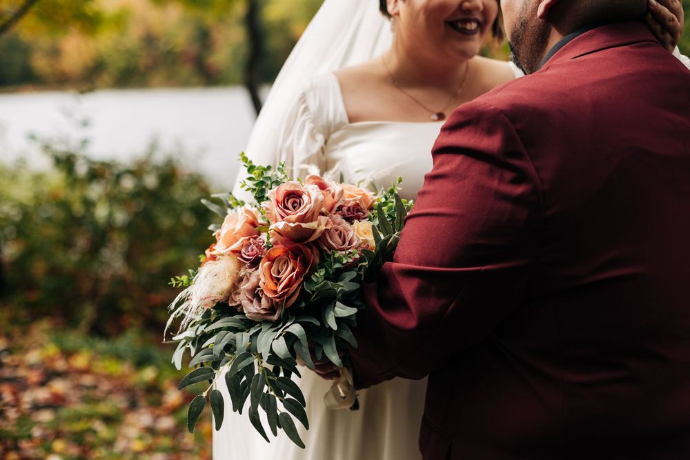 Close-up of a bridal bouquet with coral flowers and greenery.
