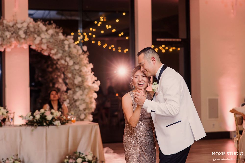 Wedding reception venue decorated with soft pink lighting and elegant floral arrangements.