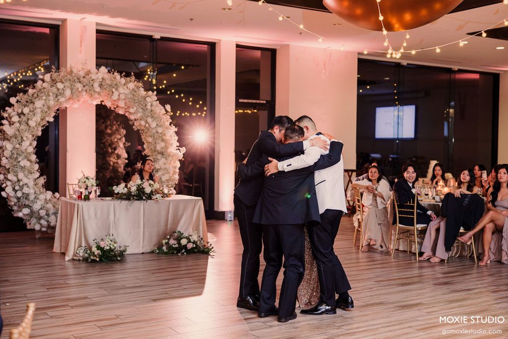 Wedding guests dancing together on an illuminated dance floor during an elegant indoor reception celebration.