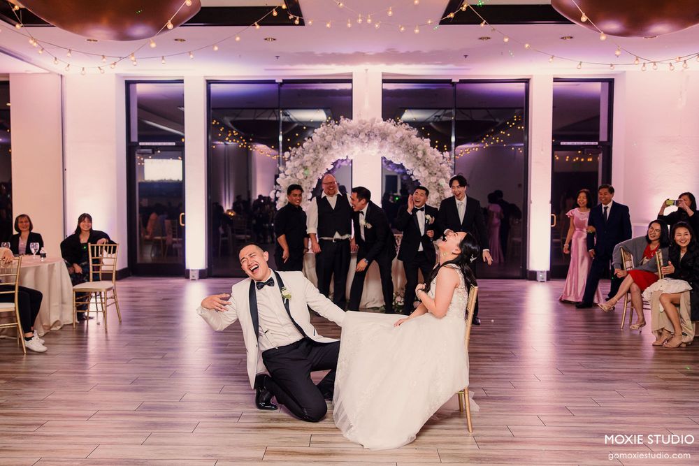 Wedding reception venue with white decor and string lights illuminated in pink lighting for an elegant celebration.