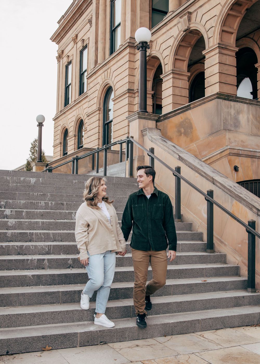 A couple walking on historic building steps in casual winter attire.
