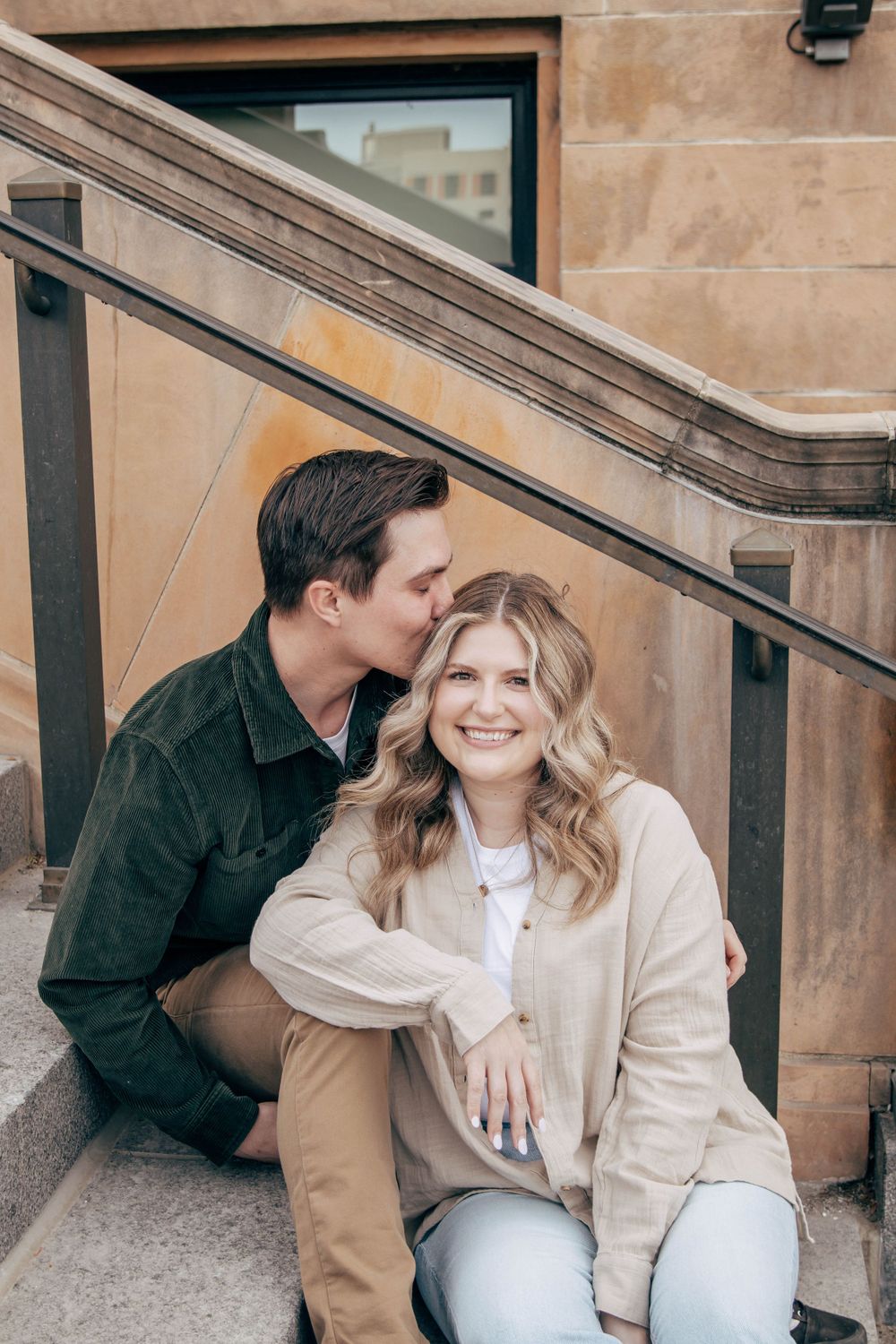 A romantic moment captured on stone steps with a couple in casual winter clothing.