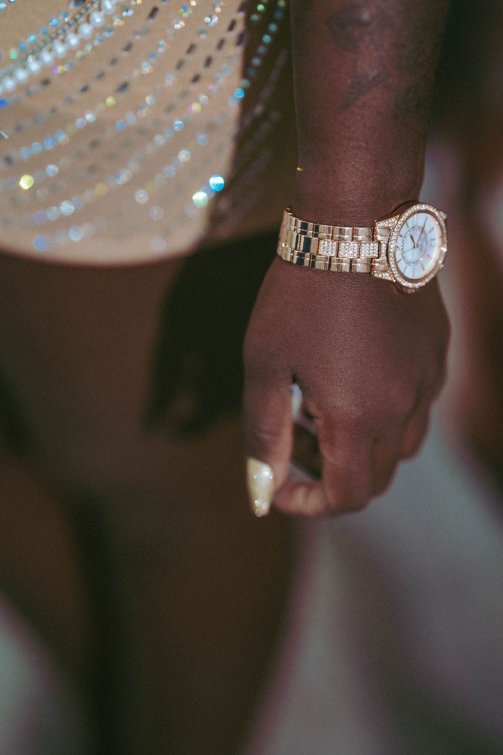 Close-up shot of wrist wearing gold watch with sparkly decorative elements.