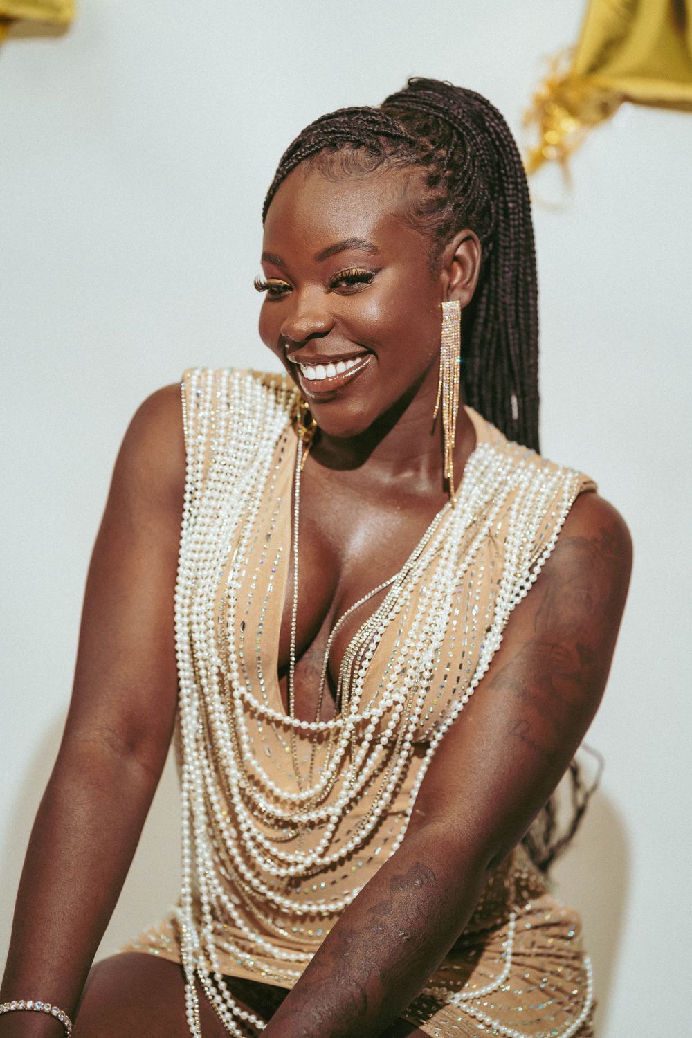 Portrait showing joyful expression and pearl-adorned formal attire against light background.