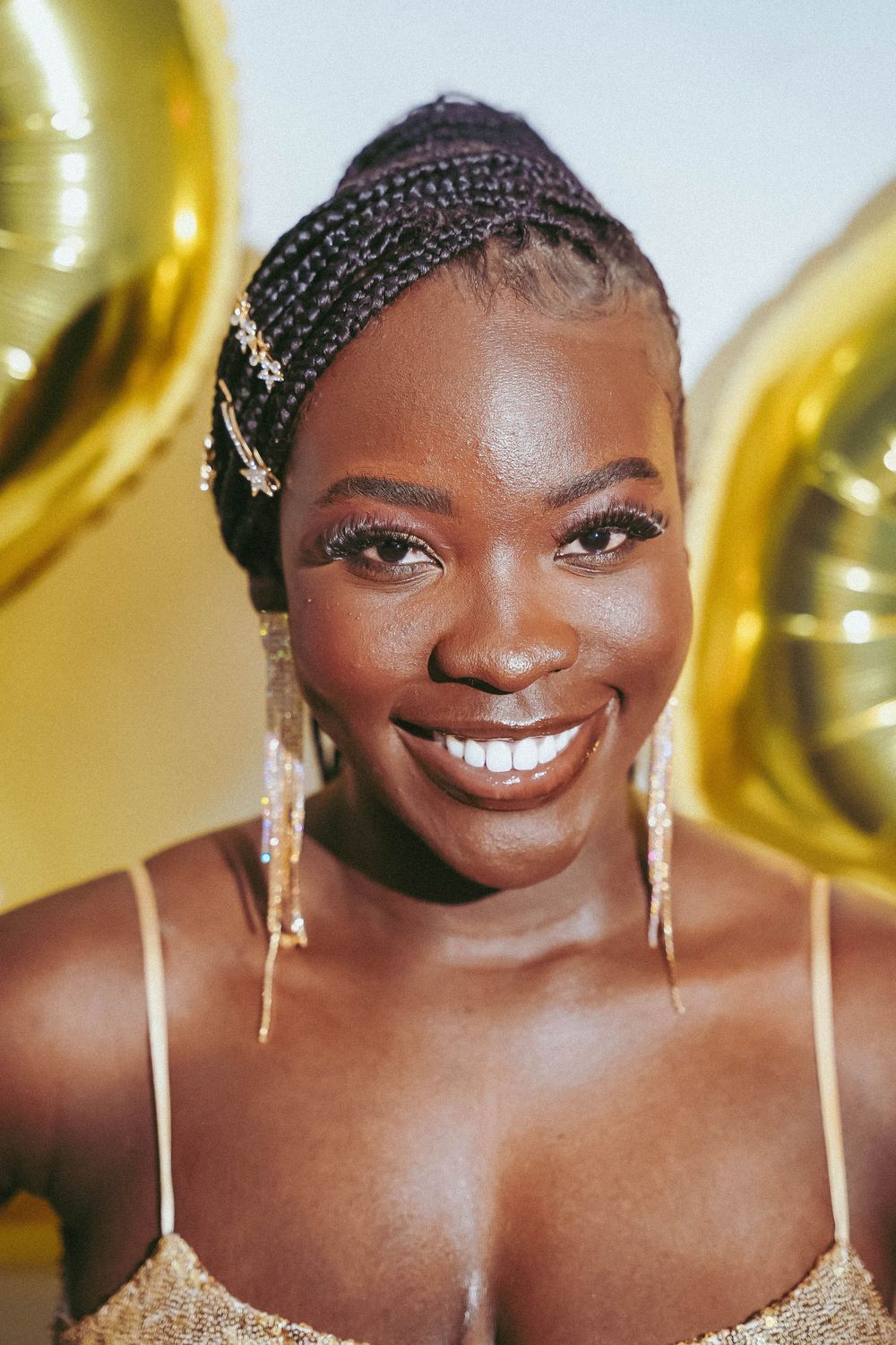 Close up portraits showing radiant smile and braided hairstyle with gold accessories.