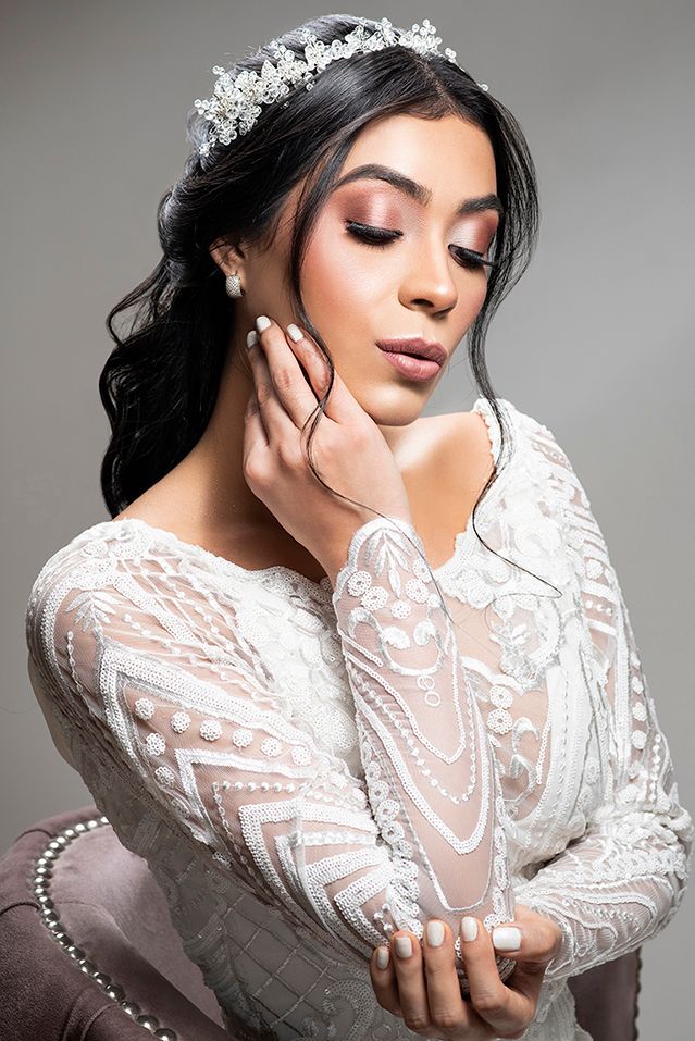 Beautiful brunette woman wearing a white lace gown and crystal tiara in an elegant bridal portrait.