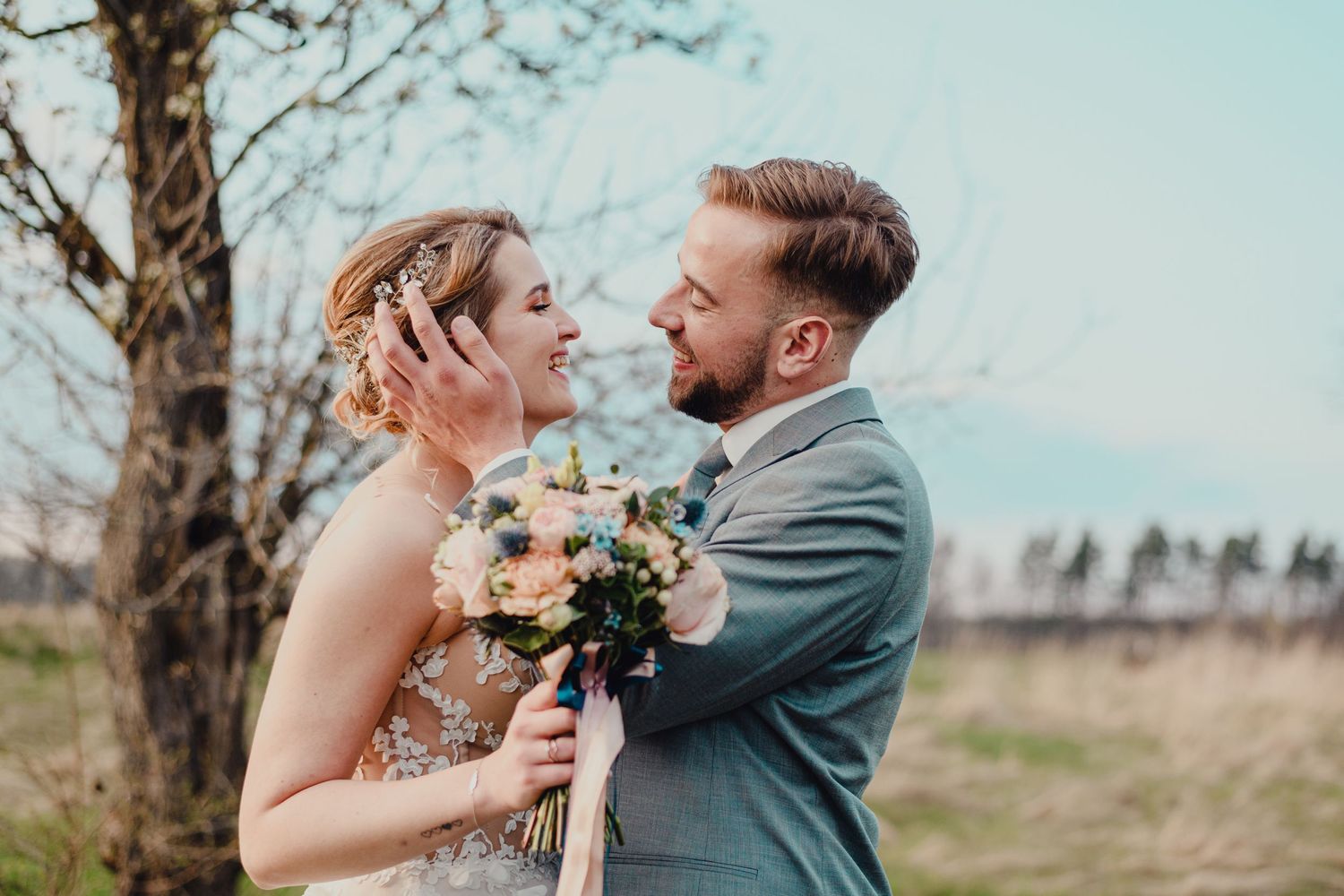 A romantic outdoor portrait of a couple embracing under blooming spring trees.
