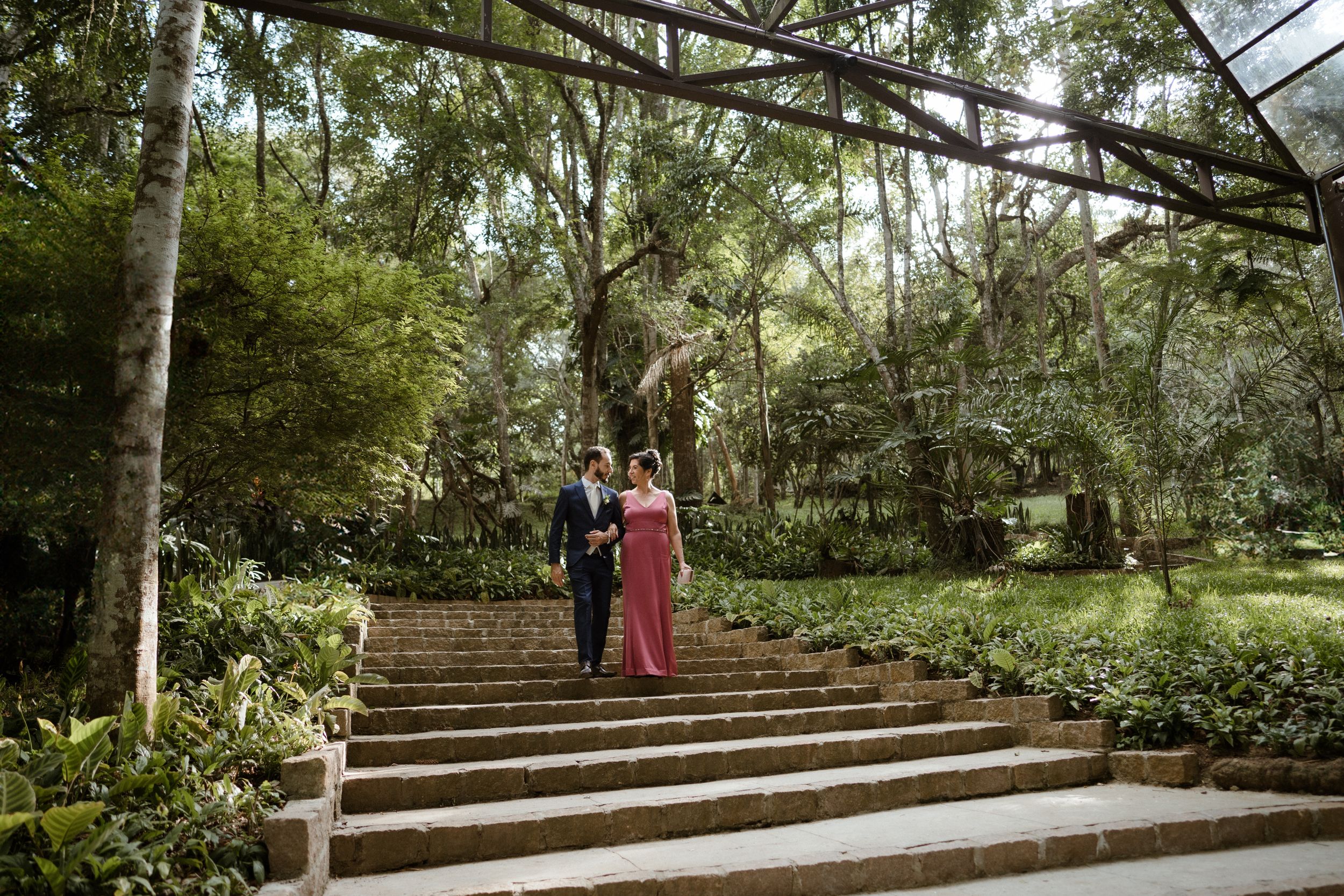 Stone steps lead up through a wooded outdoor wedding venue with seating.