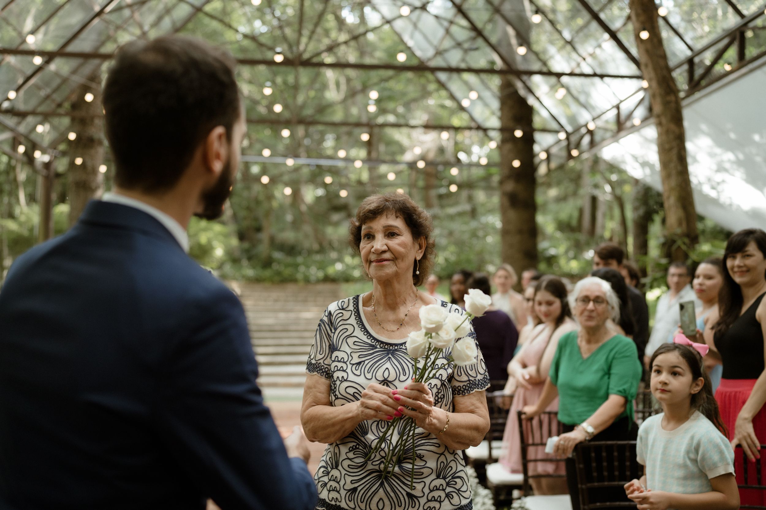 Guests gather at an outdoor wedding reception under string lights and trees.