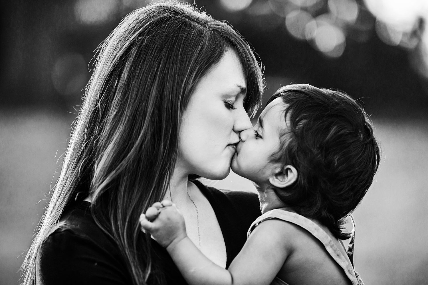 An intimate black and white portrait capturing a tender moment between parent and child.