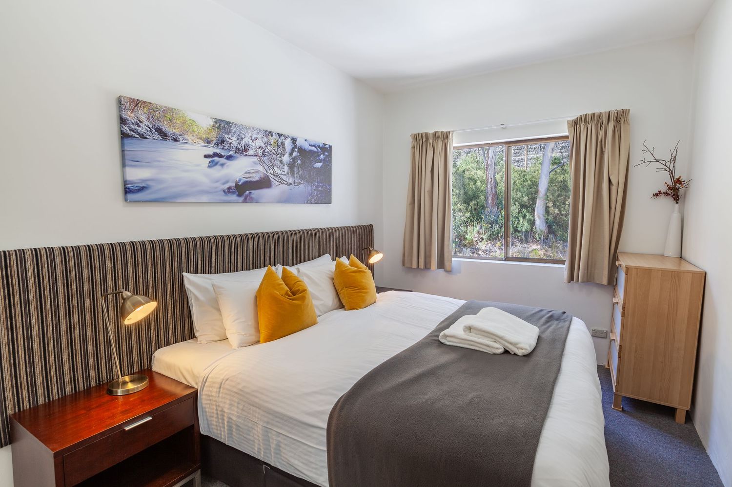 Contemporary bedroom with mountain views and modern furnishings in neutral tones.