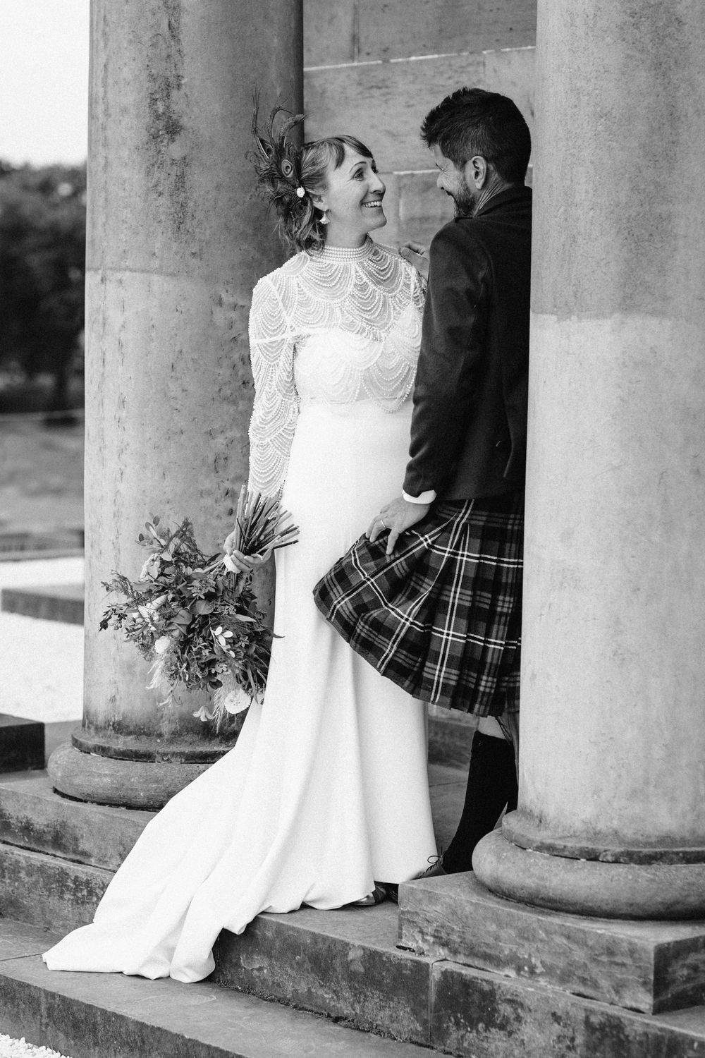 Black and white wedding photos showing a couple posing between elegant stone columns.