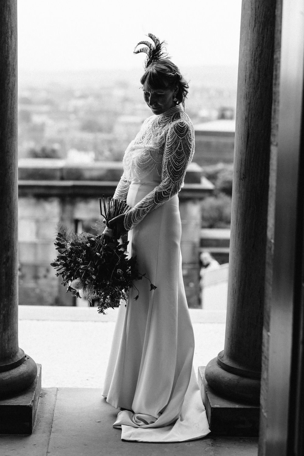Artistic black and white photos of a bride in a lace dress posing between classical columns.