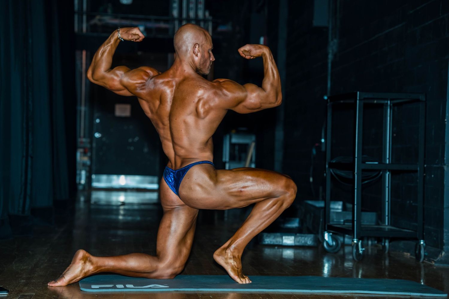 Bodybuilders showcase their physique on stage during a competition, flexing muscles and posing for judges