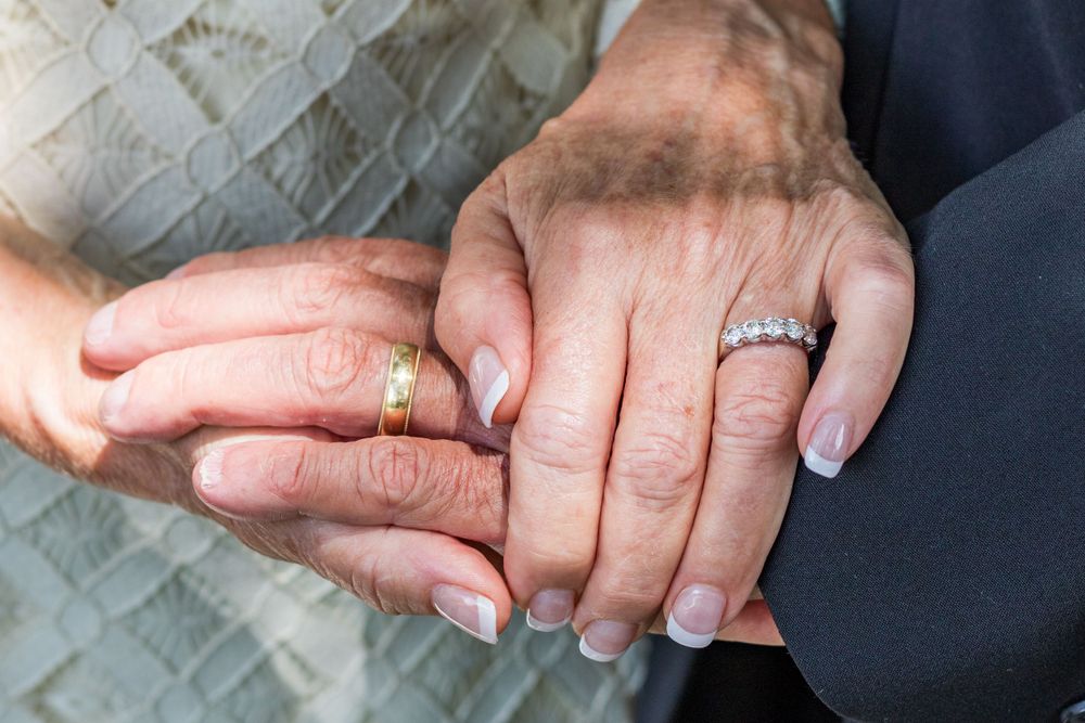 Close-up shot of hands clasped together showing wedding rings.