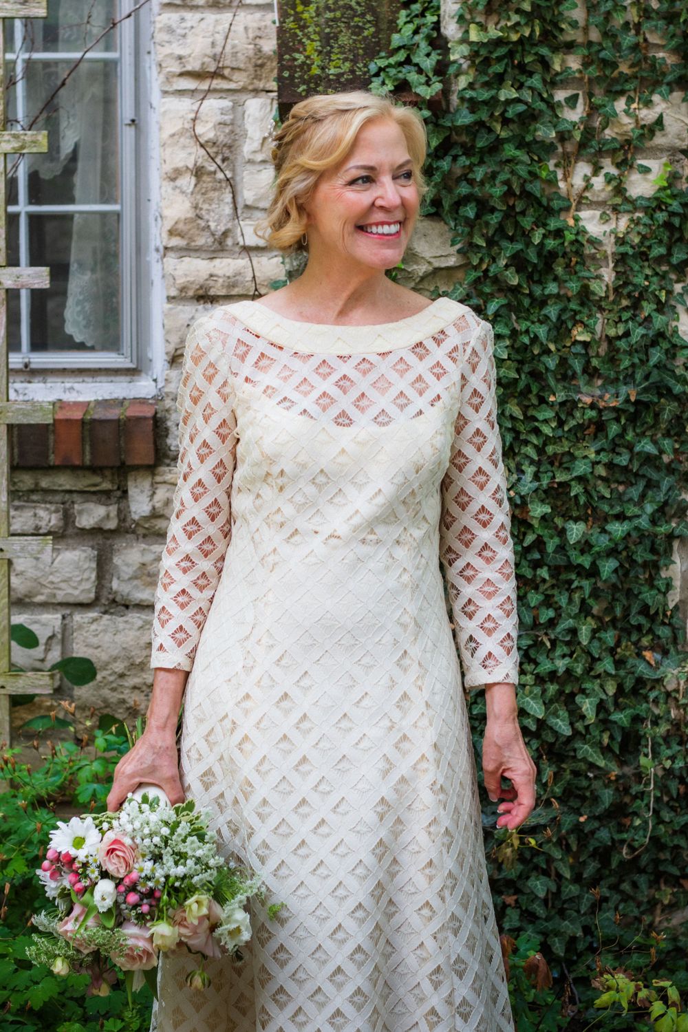 Beautiful lace wedding dress photographed against an ivy-covered stone wall.