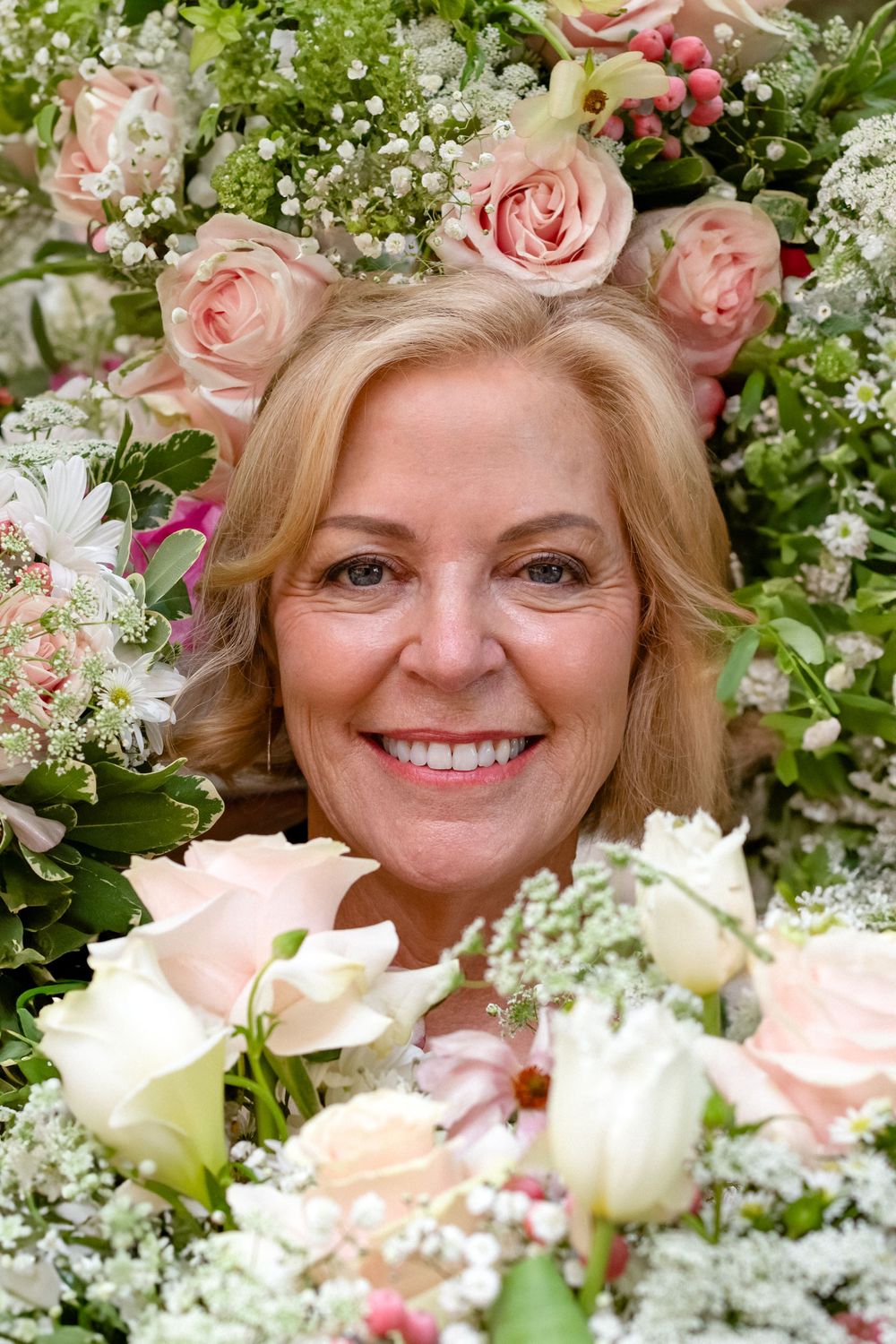 Romantic bridal portrait surrounded by pink roses and baby's breath flowers.
